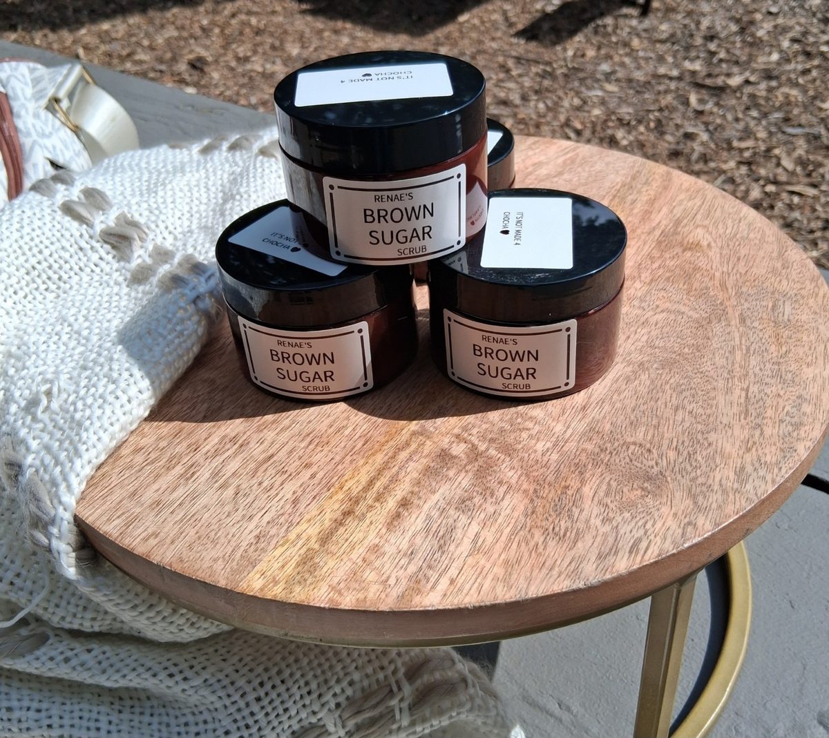 Three jars of Renae's Brown Sugar Scrub stacked on a wooden table